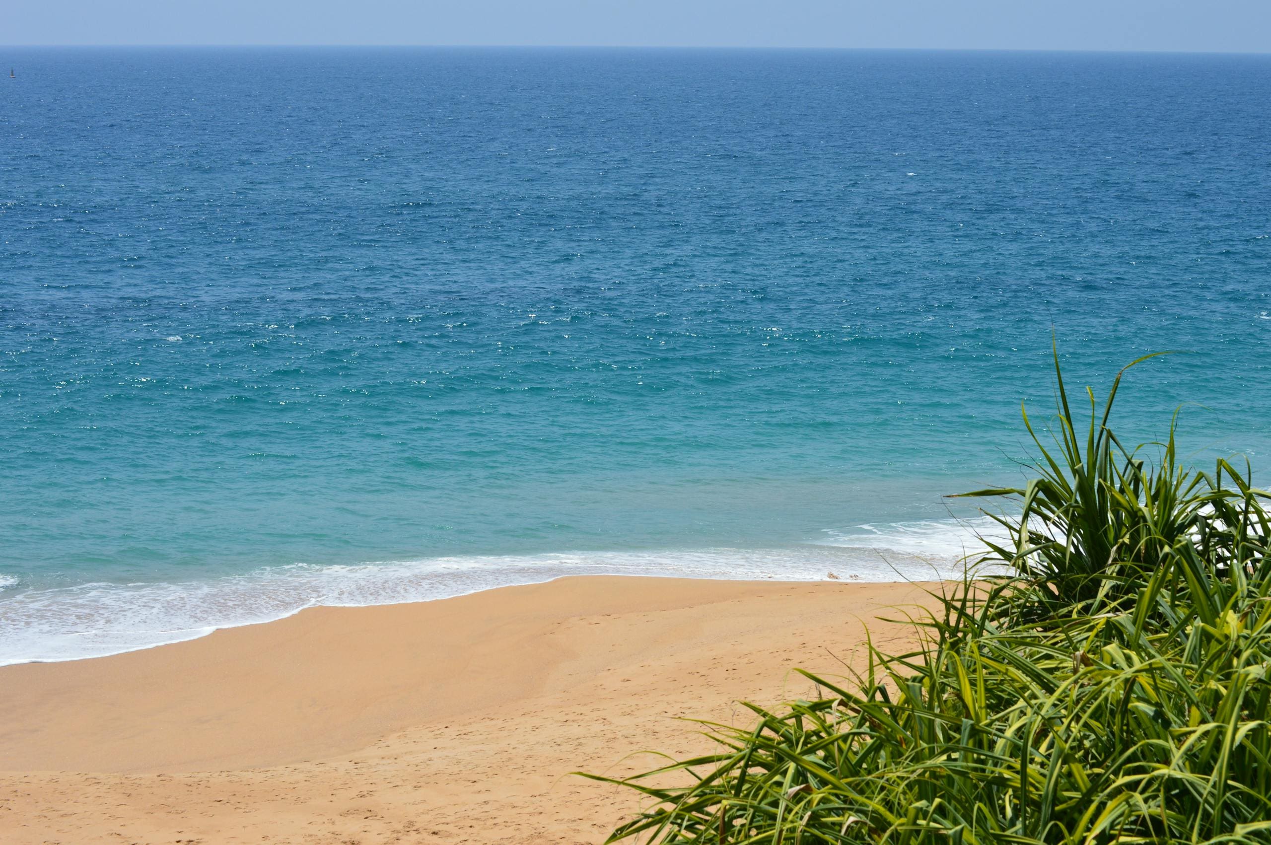 Tranquil beach scene with clear blue ocean and sky, ideal for relaxation.